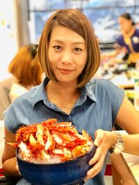 Close-up portrait of woman having seafood in bowl at restaurant