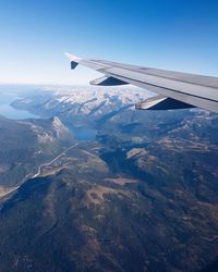 Aerial view of airplane wing over landscape against sky