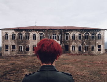 Rear view of woman standing against building