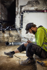 Concentrated manual worker writing notes while drilling floor in basement