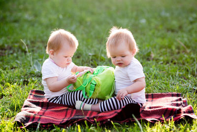 Cute twins sitting on grass at park