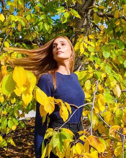 Beautiful young woman standing against yellow plants