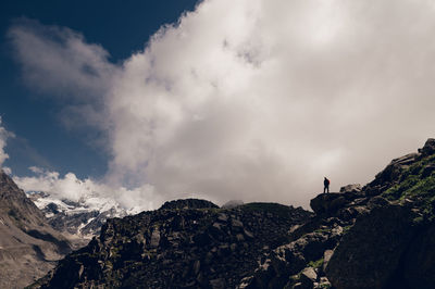 Rear view of man standing on mountain against sky