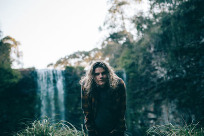 Portrait of young woman standing against trees in forest