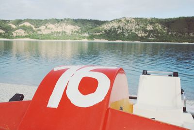 Close-up of red boat moored in lake against sky