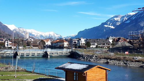 Buildings by lake against sky during winter