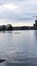 Scenic view of river by buildings against sky