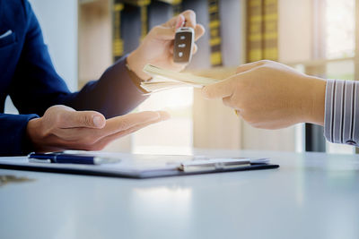 Midsection of client giving currency to insurance agent at office