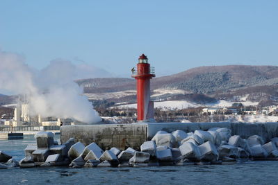 Lighthouse by sea against sky