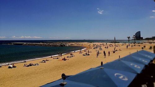 Panoramic view of people on beach against clear blue sky