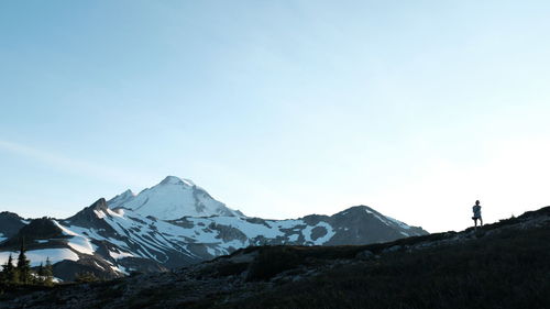 Woman walking on rocks against snow covered mountains