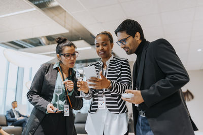 Businesswoman sharing smart phone with delegates during networking seminar