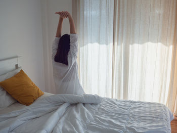 Midsection of woman relaxing on bed at home