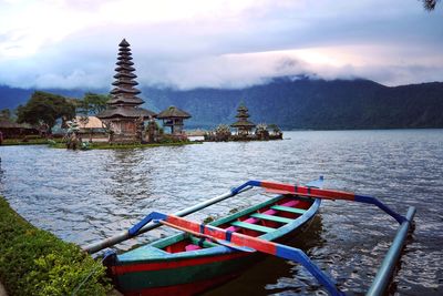 Boat in lake by building against sky