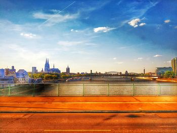 Bridge over river by buildings in city against sky