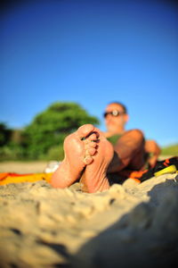 Surface level of young woman relaxing on land against clear sky