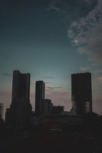 Silhouette buildings in city against sky at sunset