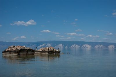 Stilt house in sea against sky