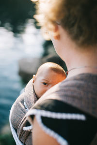 Midsection of mother carrying daughter in baby carrier