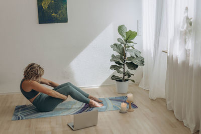 Full length of young woman exercising at home