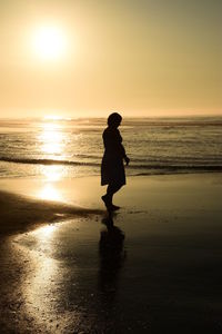 Silhouette woman at beach against sky