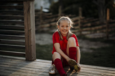 Smiling girl putting football shoes on