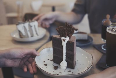 Hand holding ice cream in plate on table