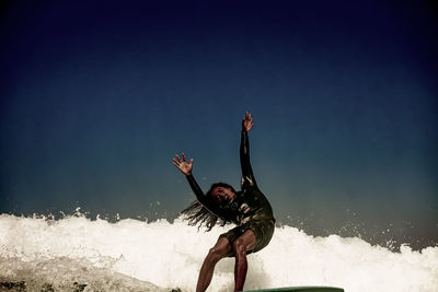 Full length of young man surfing on sea against sky