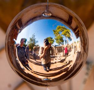 Reflection of people on mirror against clear sky