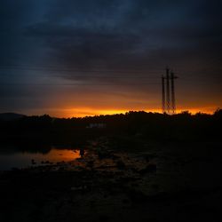Silhouette of electricity pylon at sunset
