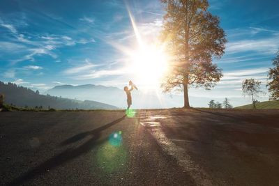 Woman with baby standing on road against sky during sunset