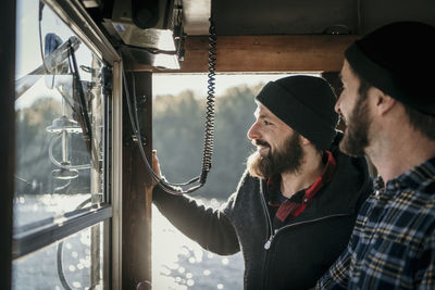 Smiling friends standing in control room of boat