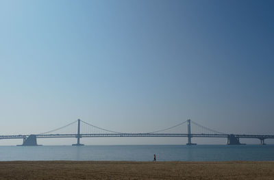 Bridge over sea against clear blue sky