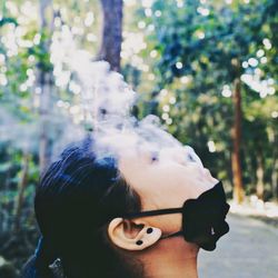 Close-up young woman smoking outdoors