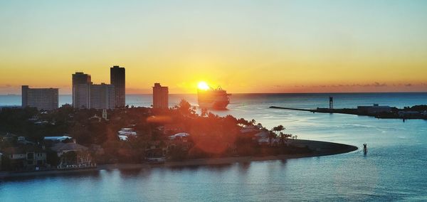 Scenic view of sea by buildings against sky during sunset