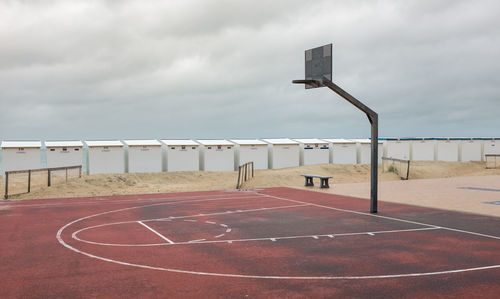 View of basketball hoop on beach against overcast sky