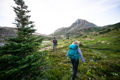 Couple hiking together into the sunset at height of the rockies