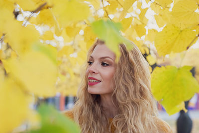 Portrait of young woman with yellow leaves