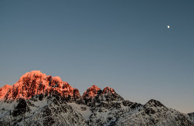 Low angle view of snowcapped mountains against clear sky