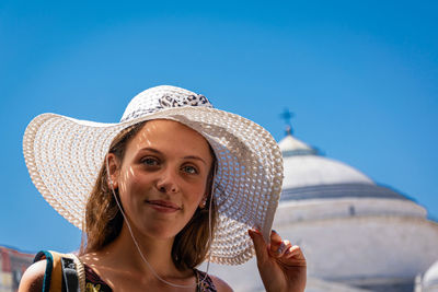 Portrait of smiling young woman against blue sky