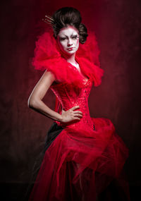 Portrait of young woman against red background