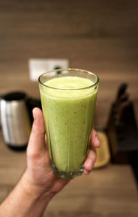 Cropped image of hand holding healthy green smoothie drink