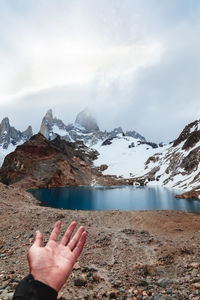 Midsection of person on snowcapped mountain against sky