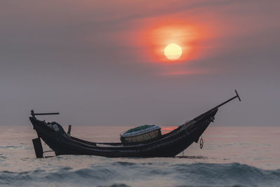 Boat on beach against sky during sunset