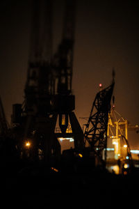 Low angle view of illuminated machine against sky at night