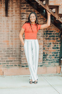 Portrait of a teenage girl standing against brick wall