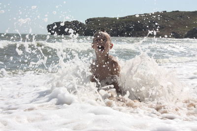 Young man splashing water in sea