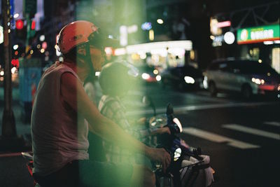 Man riding motorcycle on city street at night