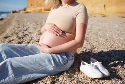 Midsection of woman sitting on land at beach