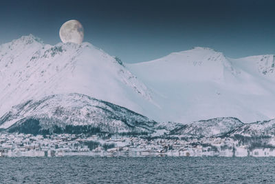 Scenic view of snowcapped mountains by sea against sky